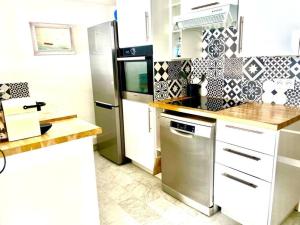 a kitchen with white cabinets and a stainless steel refrigerator at Vue mer, plages à 2 min, Cagnes-sur-mer in Cagnes-sur-Mer