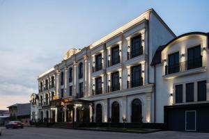a large white building with a car parked in front of it at FRANKFORT Expo Hotel in Tashkent