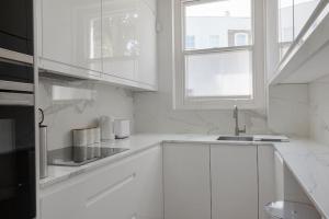 a white kitchen with white cabinets and a sink at Superb two bedroom flat in Little Venice in London