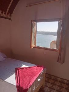 Schlafzimmer mit einem Fenster und einem Bett mit einer roten Decke in der Unterkunft Ramy Heissa Nubian house in Assuan
