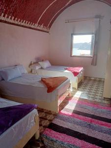 Ramy Heissa Nubian house في أسوان: غرفة بثلاث اسرة ونافذة