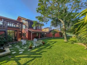 a yard with white chairs in front of a house at Casa em Geribá in Búzios
