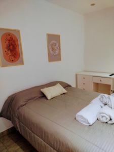 Un dormitorio con una cama con toallas blancas. en Arizona en Chascomús