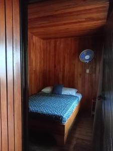 a small bedroom with a bed in a wooden room at Casa Miramar in Uvita