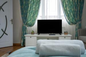 a living room with a tv on a table with curtains at Infinity Boutique Apartments in Bansko