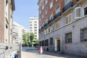 a woman walking down a street next to a building at Madrid Executive Bright y Central in Madrid