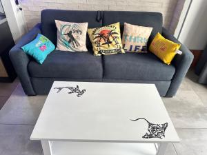 a coffee table in front of a couch with pillows at T1bis à La Hume climatisé in Gujan-Mestras