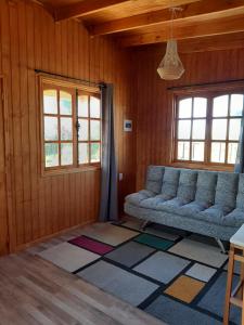 a living room with a couch and two windows at Cabañas de Campo MARBAJA in Puerto Montt