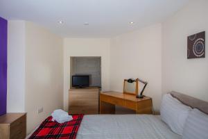 a bedroom with a bed and a desk and a television at Colourful&Bright Apartment by Carlton Hill in Edinburgh
