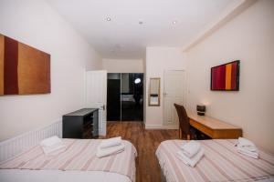 a hotel room with two beds and a desk and a desk at Colourful&Bright Apartment by Carlton Hill in Edinburgh