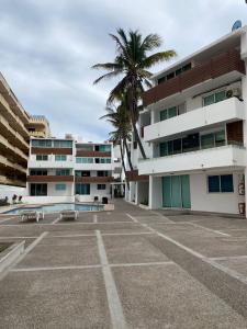 un aparcamiento frente a un edificio con una palmera en Marina del Sol Resort Condo directly on the Ocean 102 en Mazatlán