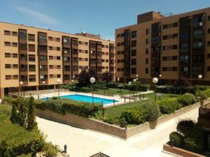 an apartment complex with a swimming pool in front of buildings at Charming Madrid Airport in Madrid