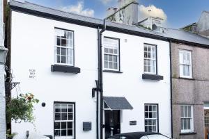 a white house with a black door and windows at Higher Cottage with Parking in Dartmouth