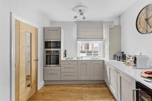 a kitchen with white cabinets and a clock on the wall at Higher Cottage with Parking in Dartmouth