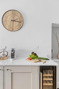 a clock on the wall above a kitchen counter with a plate of vegetables at Higher Cottage with Parking in Dartmouth +9 photos