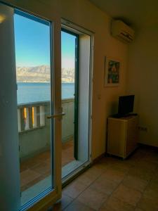 a room with a sliding glass door with a view of the ocean at Molo Lozna Apartments in Postira