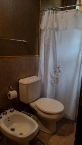a bathroom with a toilet and a white shower curtain at Yvyra Lodge in San Ignacio +14 photos