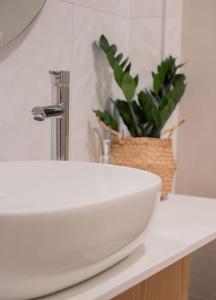 um balcão de casa de banho com um lavatório branco e uma planta em Boutique 27, luxury apartment. em Ioannina