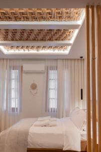 um quarto com uma cama com lençóis brancos e janelas em Boutique 27, luxury apartment. em Ioannina