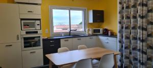 eine kleine Küche mit einem Tisch und einem Fenster in der Unterkunft loft près futuroscope in Montamisé