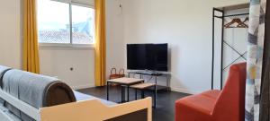 ein Wohnzimmer mit einem TV, einem Sofa und einem Stuhl in der Unterkunft loft près futuroscope in Montamisé