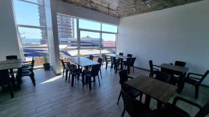 a dining room with tables and chairs and windows at Vistara Suites in Iquique