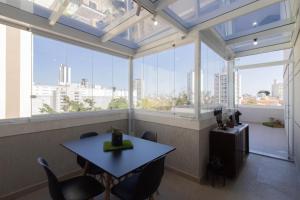 a table and chairs in a room with large windows at Cobertura 2 quartos Tucuruvi in Sao Paulo