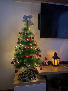 Un árbol de Navidad está en una mesa con una lámpara en Aleksić Apartment Zlatibor, en Zlatibor