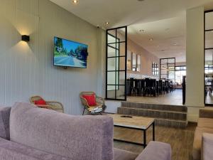 a living room with a couch and a tv on the wall at Tierra Gaucha Hostel Boutique in San Carlos de Bariloche