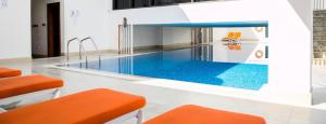 a swimming pool with orange chairs and orange stools at Elite LUX Holiday Homes - One Bedroom Apartment in Silicon Oasis, Dubai in Dubai