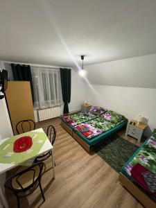 ピブニチュナ・ズドルイにあるHelenaのベッド2台、テーブル、椅子が備わる客室です。