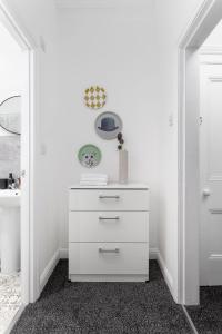 a white dresser in a room with white walls at Host Liverpool - Cozy Home near Univ & Hospital,1mi to Station in Liverpool