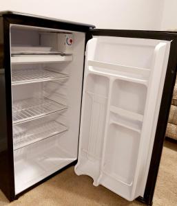 un réfrigérateur vide avec une porte ouverte dans une pièce dans l'établissement Lovely comfy home private bath in central Calgary, à Calgary