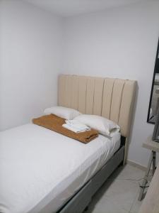 Una cama con sábanas blancas y almohadas. en Edif HA, en Cartagena de Indias