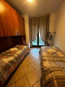 a hotel room with two beds and a window at La Corte Sul Lago casa vacanze in Pisogne