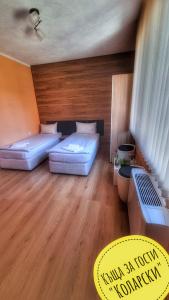 2 letti in una camera con pavimento in legno di Къща за гости Коларски a Sapareva Banya