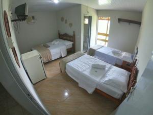 a hotel room with two beds and a television at Pousada Solar da Montanha in Pedreira