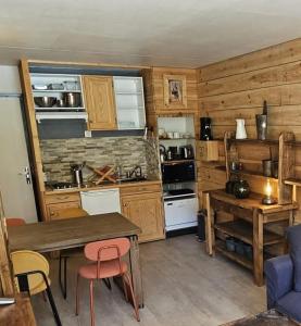 - une cuisine avec des placards en bois, une table et des chaises dans l'établissement Studio La Mongie - Tourmalet au pied des pistes, à La Mongie