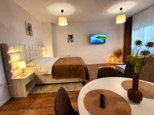 a hotel room with a bed and tables and chairs at Garden City Studio in Sibiu