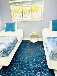 two beds in a room with a blue carpet at Monaco villa Gaborone in Gaborone