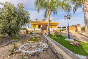 una casa con una fuente en un patio con palmeras en Casa Rural en el entorno de Doñana, en Hinojos
