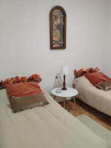 a bedroom with two beds and a table with a lamp at La casita del vino in Socuéllamos