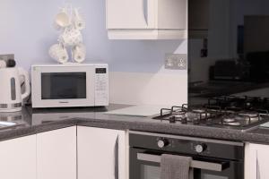 a kitchen with a stove and a microwave at Constancevilla B9 - Grampian Lettings Ltd in Aberdeen