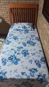 a bed with a blue floral bedspread on it at Quartos aconchegantes na praia do francês in Marechal Deodoro