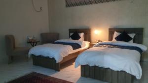 a bedroom with two beds and a chair at Bloom Rooms in Islamabad