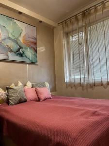sypialnia z łóżkiem z różową pościelą i oknem w obiekcie Apartment Bombonjera w mieście Užice