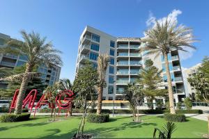 ein großes Apartmenthaus mit einem Schild in einem Park in der Unterkunft Elite LUX Holiday Homes - Modern One Bedroom Apartment in MAG 5, Dubai South in Dubai