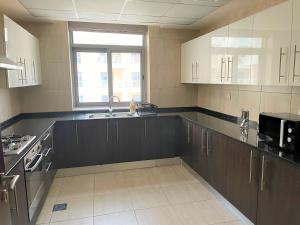 eine Küche mit braunen Schränken, einem Waschbecken und einem Fenster in der Unterkunft Elite LUX Holiday Homes - Two Bedroom Apartment Direct Metro Access in Al Furjan, Dubai in Dubai