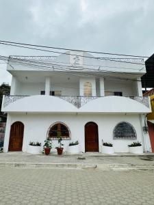 un bâtiment blanc avec des portes et des plantes en pot devant dans l'établissement Casa Palmamar, à Olón