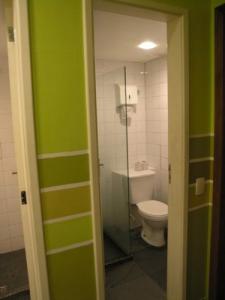 a bathroom with a toilet and a green wall at Arcos Da Lapa Hostel in Rio de Janeiro